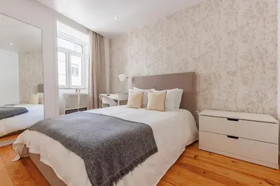 a bedroom with a large white bed and a window at Cozee Bonjardim in Porto