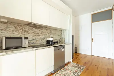 a kitchen with white cabinets and a microwave at Home M apartments in Porto