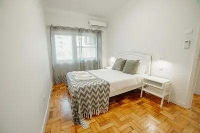 a bedroom with a white bed and a wooden floor at Cedofeita Flat by Hosty in Porto