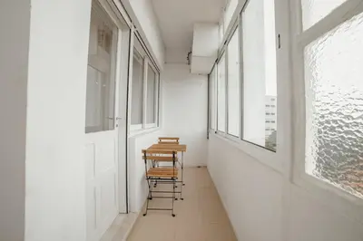 a hallway with a table and chairs in a room with windows at Cedofeita Flat by Hosty in Porto