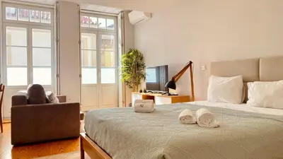 a bedroom with a bed with a laptop and a chair at SM Apartments in Porto
