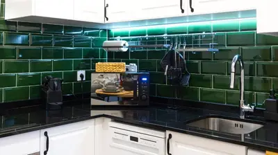 a kitchen with black counter tops and green tiles at Trendy 2BR Near Douro River by LovelyStay in Vila Nova de Gaia