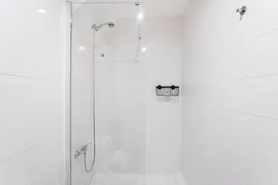 a white bathroom with a shower with a glass door at GuestReady - Oporto Old Town House 2 in Porto
