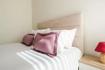 a white bed with white pillows and a red lamp at Wonderfull apartment Campanhã Train station with parking in Porto
