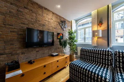 a living room with a couch and a tv on a brick wall at Merc Porto Downtown's Place in Porto