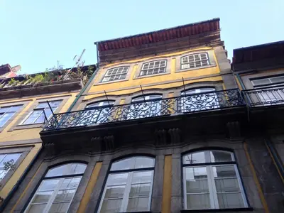 a tall yellow building with a balcony at Merc Porto Downtown's Place in Porto