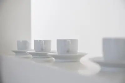 a row of white coffee cups sitting on saucers at GuestReady - Souto Downtown Studios in Porto