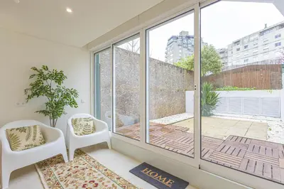 a room with a large window and two chairs at Marilia's Garden Apartment in Porto