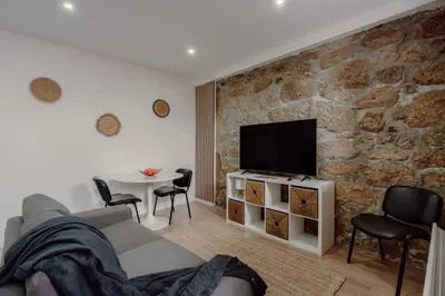 a living room with a stone wall with a tv at Yellow House by Best2Stay in Vila Nova de Gaia