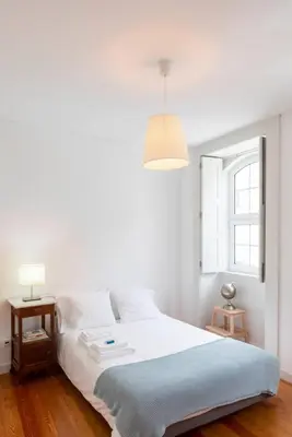a bedroom with a white bed with a lamp and a window at A House With A View - 1st floor in Porto