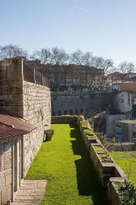 a garden with grass and a stone wall at A House With A View - 1st floor in Porto