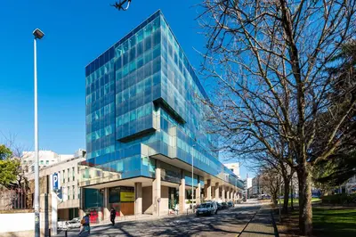 a tall glass building on a city street at DoisPontoZero Campo 24 Agosto in Porto