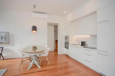 a kitchen with white cabinets and a table and chairs at Liiiving in Porto - Downtown & Riverside Balcony in Porto