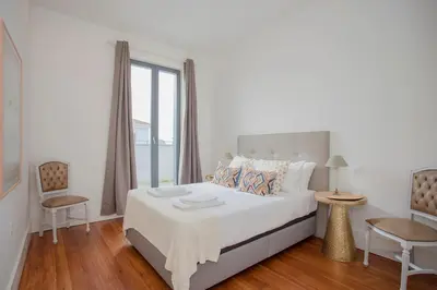 a white bedroom with a bed and a window at Liiiving in Porto - Downtown & Riverside Balcony in Porto