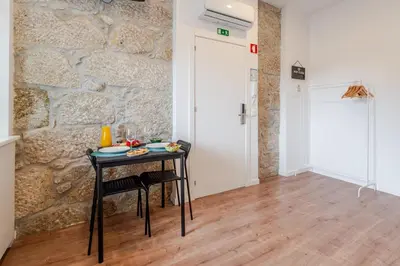 a table with two chairs in a room with a stone wall at HostWise - Stylish Sunny Flats in Porto