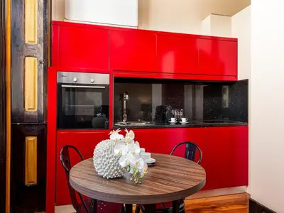 a red kitchen with a wooden table and red cabinets at Studio near Ribeira do Porto in Porto