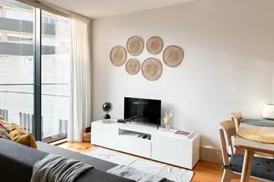 a white living room with a television and a table at Ekaterine Uptown in Porto