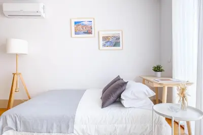 a white bedroom with a bed and a table at Ekaterine Uptown in Porto