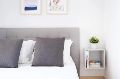 a bed with white sheets and grey pillows and a nightstand at Ekaterine Uptown in Porto