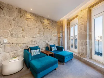 a room with two blue chairs and a stone wall at City Apartment with River Views in Vila Nova de Gaia