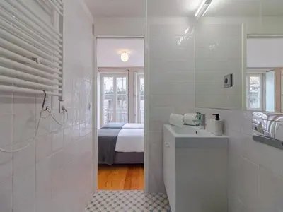a white bathroom with a sink and a bed at Modern studio in Porto with balcony in Porto
