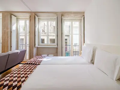 a bedroom with two beds and two windows at Central Porto apartment with balcony in Porto
