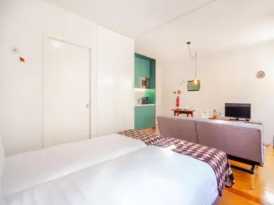 a white room with a bed and a desk at Central Porto apartment with balcony in Porto