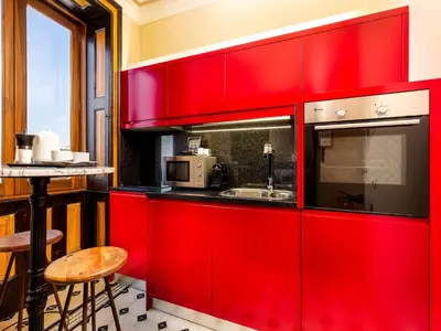 a red kitchen with a sink and a counter at Beach studio nearby market in Oporto in Porto