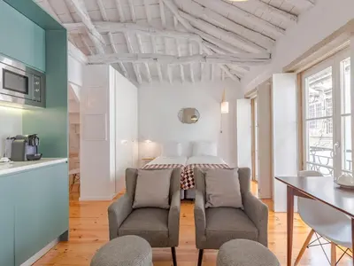 a room with a bed and two chairs and a table at Stylish Porto studio with city views in Porto