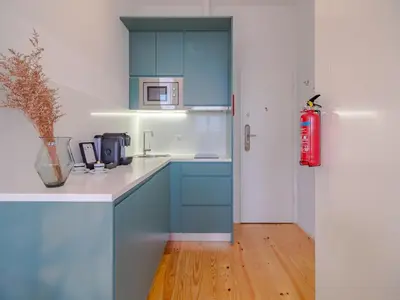 a kitchen with blue cabinets and a red fire extinguisher at Stylish Porto studio with city views in Porto