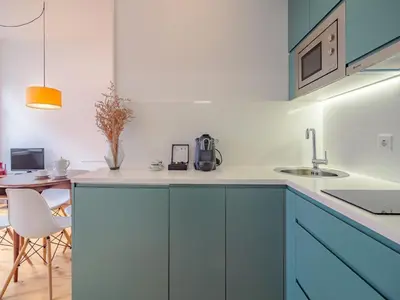 a kitchen with blue cabinets and a dining table at Stylish Porto studio with city views in Porto