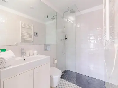 a white bathroom with a shower and a toilet at Stylish Porto studio with city views in Porto