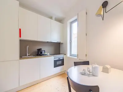 a kitchen with white cabinets and a table with chairs at Charming studio, ideal for smaller groups in Porto