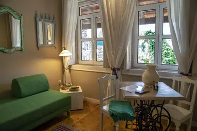 a living room with a green couch and a table and windows at Cedofeita Village in Porto