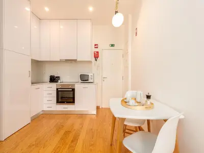 a kitchen with white cabinets and a white table and chairs at Stylish City-Center Retreat in Porto