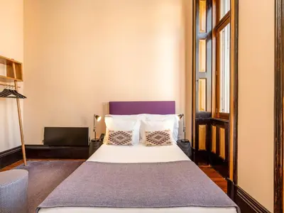 a bedroom with a white bed with a purple headboard at Charming Porto Studio Central & Cozy in Porto