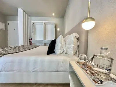 a bedroom with a white bed and a table with a vase at Compact & Cozy Retreat in Porto s Heart in Porto