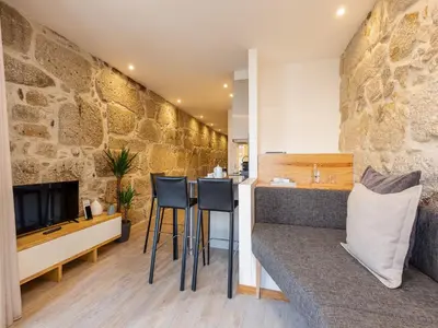 a kitchen with a stone wall and a counter with stools at Modern & Cozy apartment, by the beach in Vila Nova de Gaia