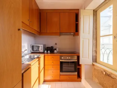 a kitchen with wooden cabinets and a sink and a microwave at Charming 1-Bedroom Apartment in Oporto in Porto
