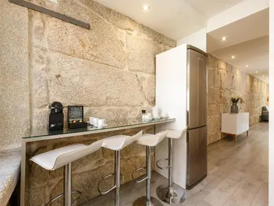 a kitchen with a bar with stools and a refrigerator at River-View Retreat in Porto in Porto