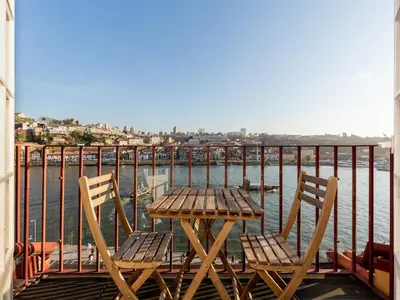 a wooden table and chairs on a balcony overlooking the water at River-View Retreat in Porto in Porto