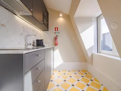 a small kitchen with a yellow and white checkered floor at City-center apartment with modern comforts in Porto