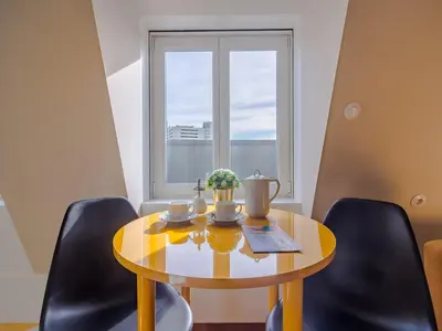 a dining room table with chairs and a window at City-center apartment with modern comforts in Porto