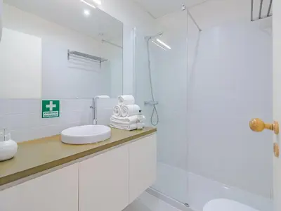 a white bathroom with a sink and a shower at Central Porto Comfort Stay in Porto