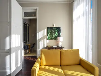 a yellow couch in a living room with a window at Modern apartment in Porto's Vibrant Heart in Porto