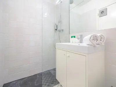 a white bathroom with a sink and a shower at Charming studio, ideal for smaller groups in Porto