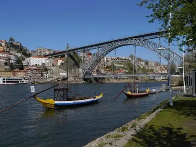 two boats are in the water under a bridge at 1-bedroom beautiful apartment in Oporto in Porto