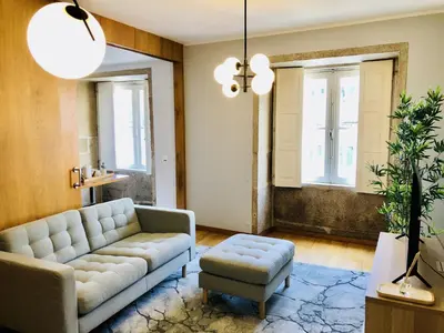 a living room with a couch and a stool and windows at Cozy City Family Retreat in Porto