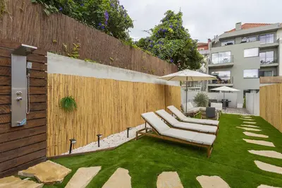a patio with lounge chairs and an umbrella on the grass at Liiiving in Porto - Pool Paradise Apartments in Porto