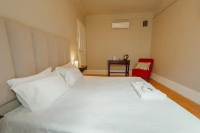 a bedroom with a large white bed with a red chair at Boutique Suites by Hosty in Porto